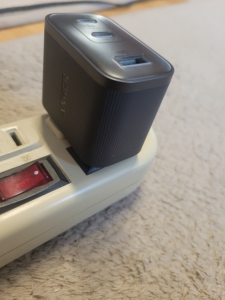 スイッチ付きコンセントに縦向きで挿した本体がスイッチに接触している状態